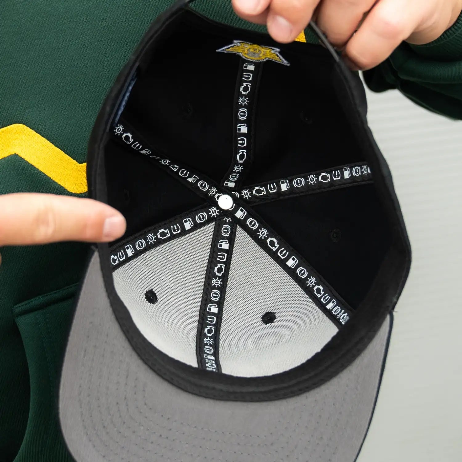 Innenansicht der schwarzen KUNDE! Cap mit kleinen gestickten Auto-Symbolen wie Tankanzeige, Motorkontrollleuchte und Reifendruckanzeige.
